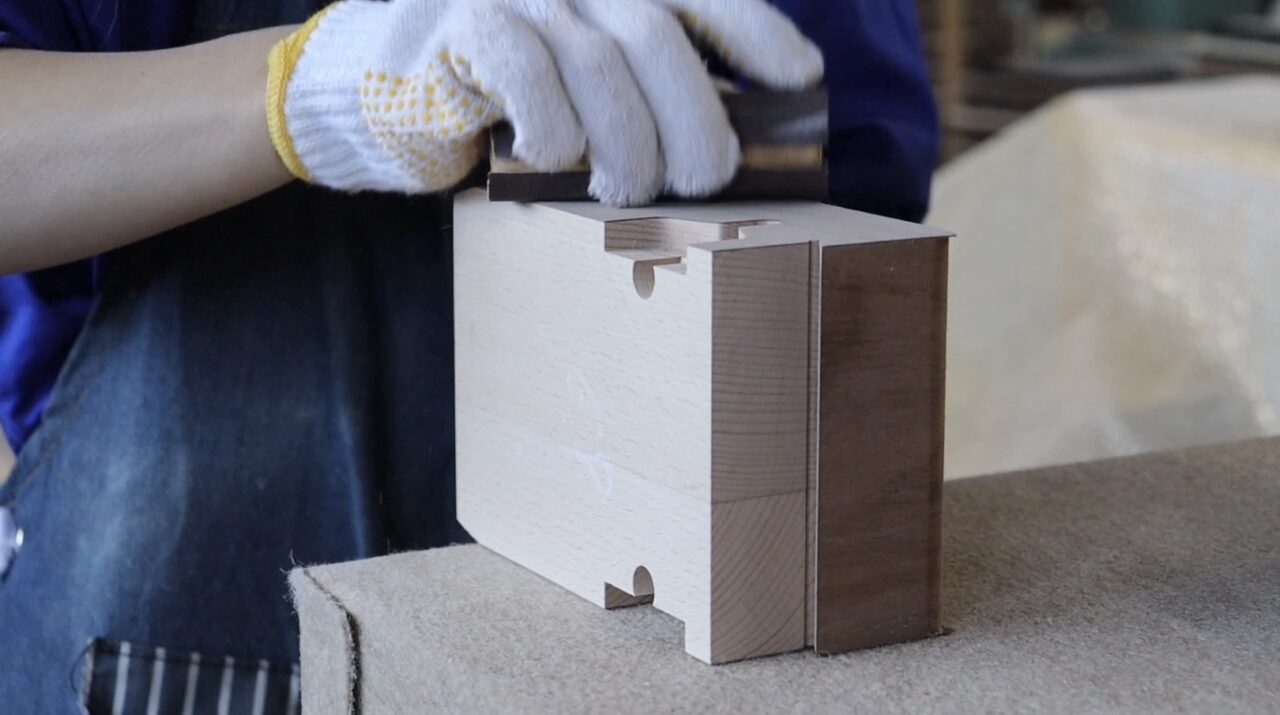 "Hand finishing process: Sanding the surface with paper to achieve a smooth finish.