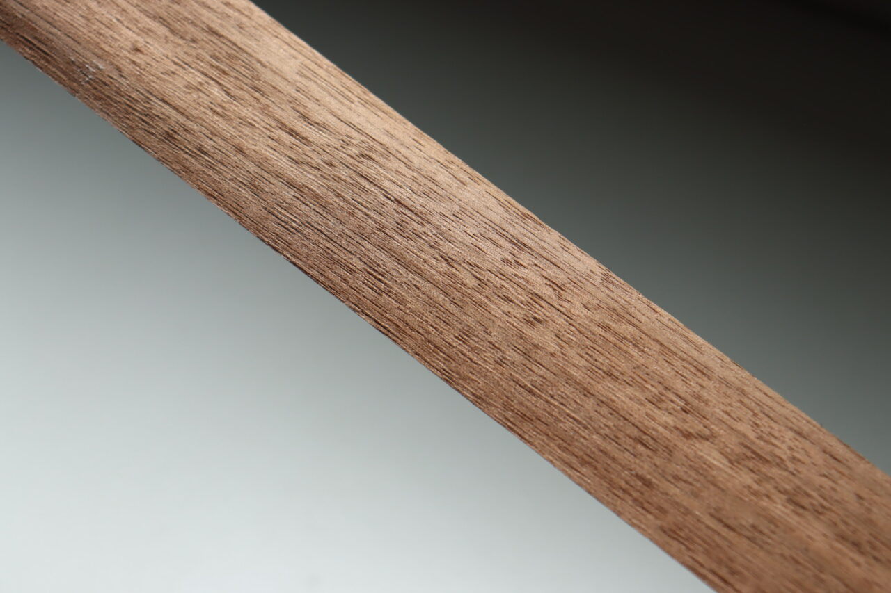 Close-up of walnut wood showcasing its rich color and grain pattern. Walnut is one of the three major luxury woods used in furniture making, known for its high density and resistance to scratches and dents.
