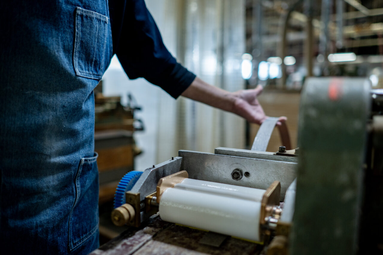Applying adhesive to long materials using a spreader (gluing machine) in a woodworking process.
