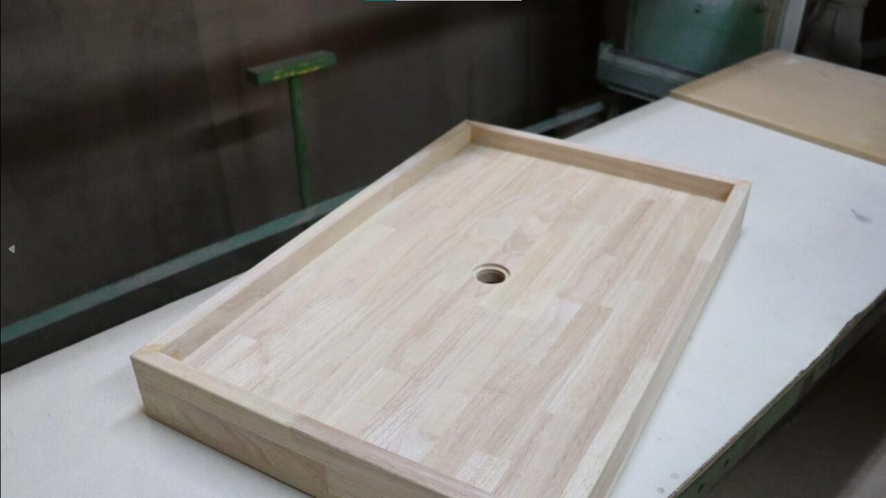 「集成材を使用したモダンなデザインのキャビネットの天板部分。木目調の仕上げが特徴で、実用的な収納機能が前面に配置されています。