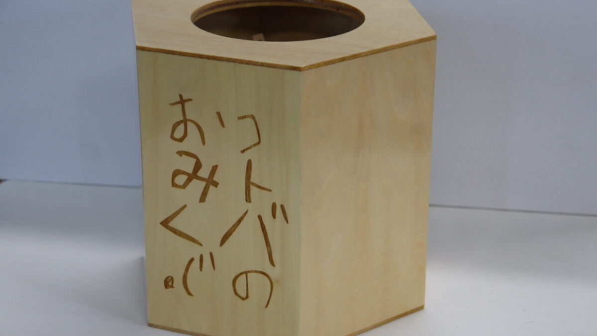 ウレタン塗装仕上げの木製おみくじ箱に手書き風の文字がレーザー彫刻されているデザイン