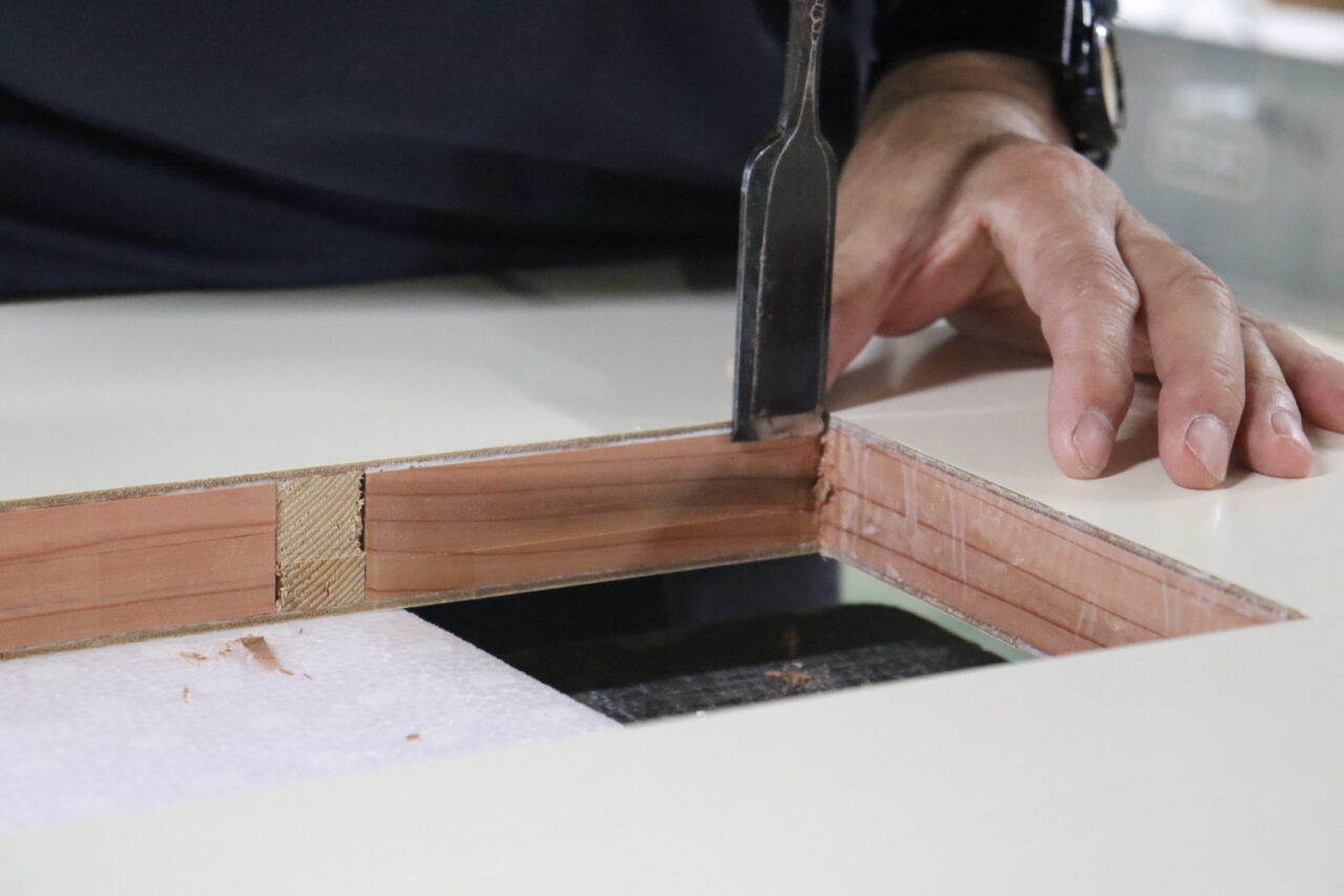 木工職人が鑿を使い、フラッシュ戸の窓枠用の開口部を手作業で切り抜く様子