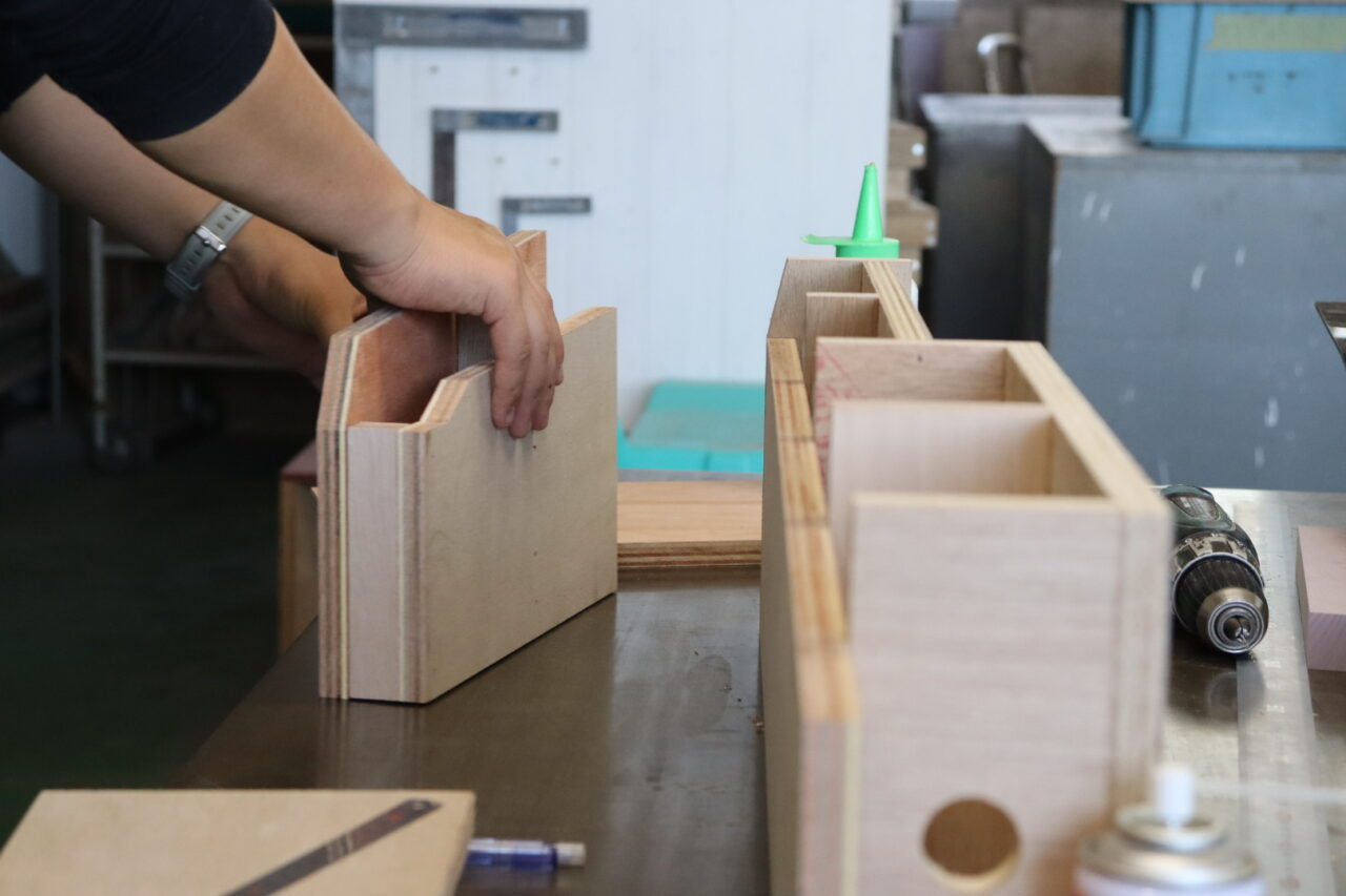 株式会社スズハルの合板加工技術を活用して、真空成形用BOXの組み立てを行う作業者