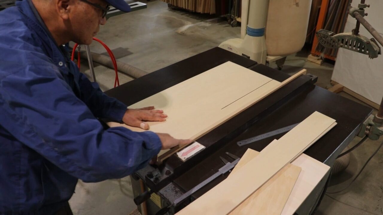式会社スズハルの木工職人がベンチソーを使用してシナ合板をカットしている作業風景