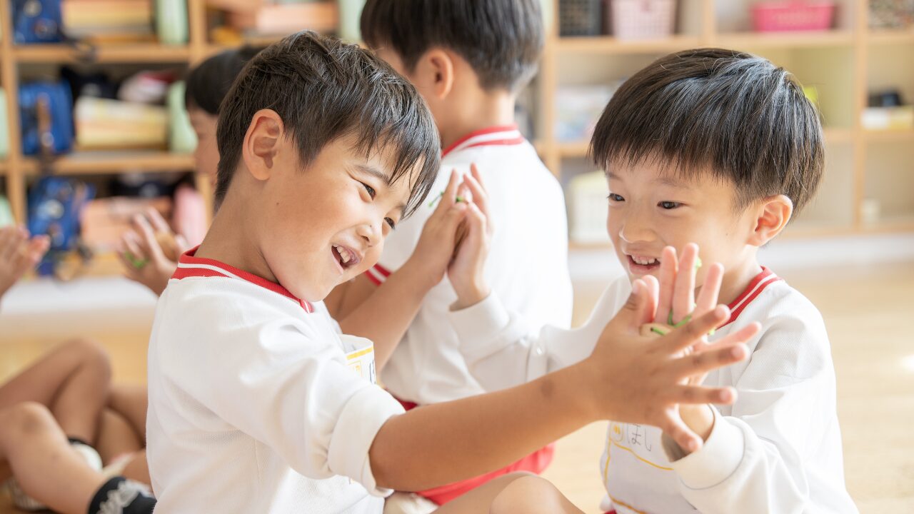 「アソカ学園城北幼稚園の園児たちが、株式会社スズハルの音育カスタネット『あそおと』を手に持ち、笑顔でハイタッチしている様子