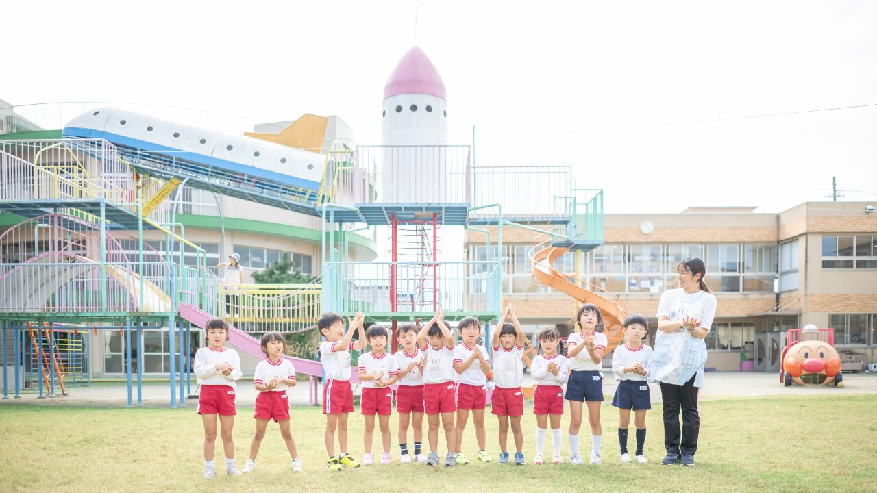 アソカ学園城北幼稚園の園児たちが屋外で、株式会社スズハルの音育カスタネット『あそおと』を楽しそうに演奏している集合写真
